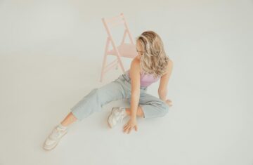 kobieta w jeansach, różowej koszulce i sneakersach